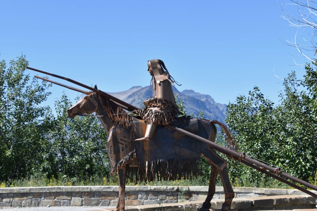 an iron sculpture of a person on horseback in front of a mountain