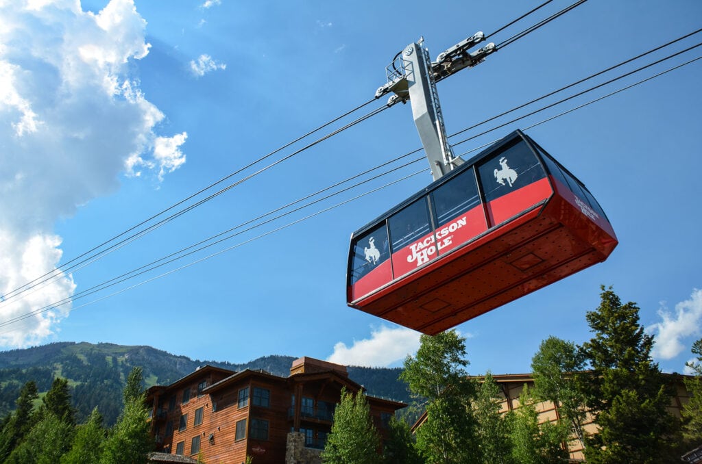 View from below of a red gondola car against a blue sky