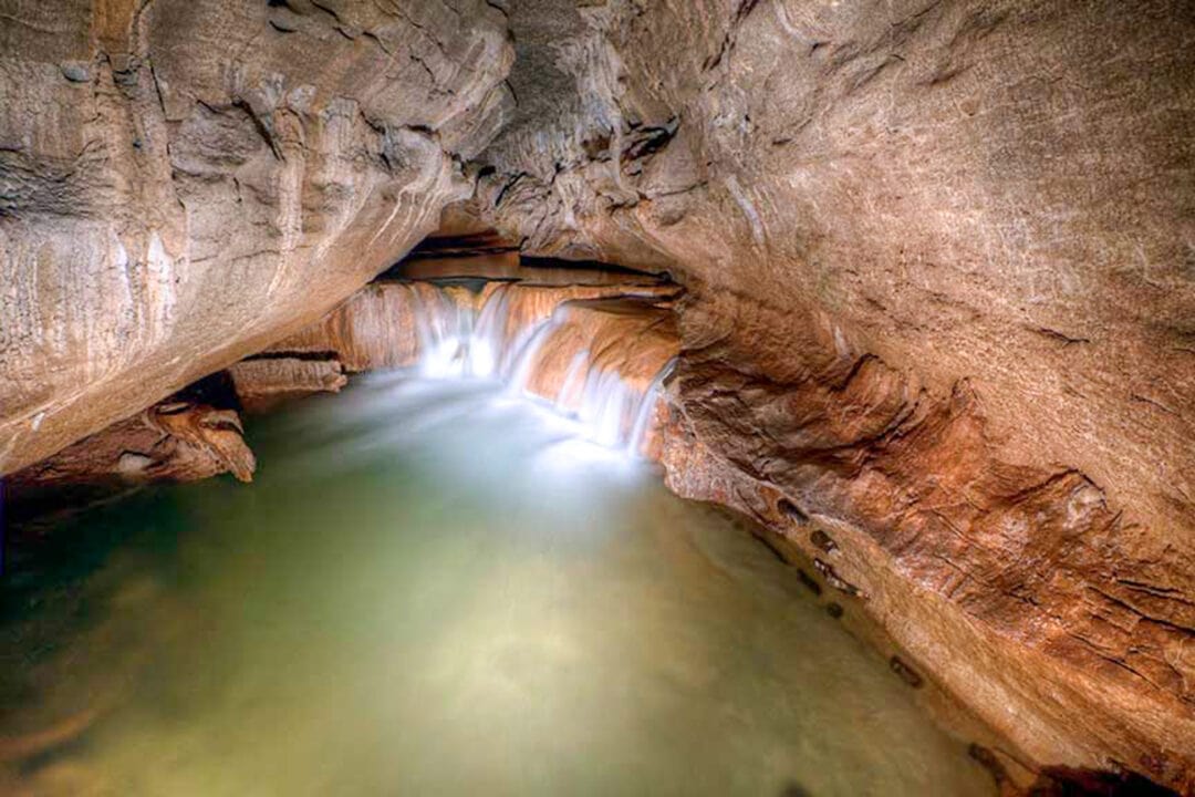 a long exposure of an underground waterfall surrounded by rock