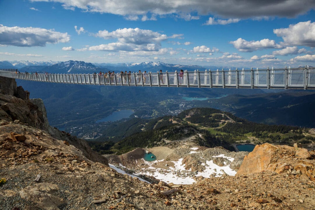 a suspension bridge with pedestrians over a mountain valley