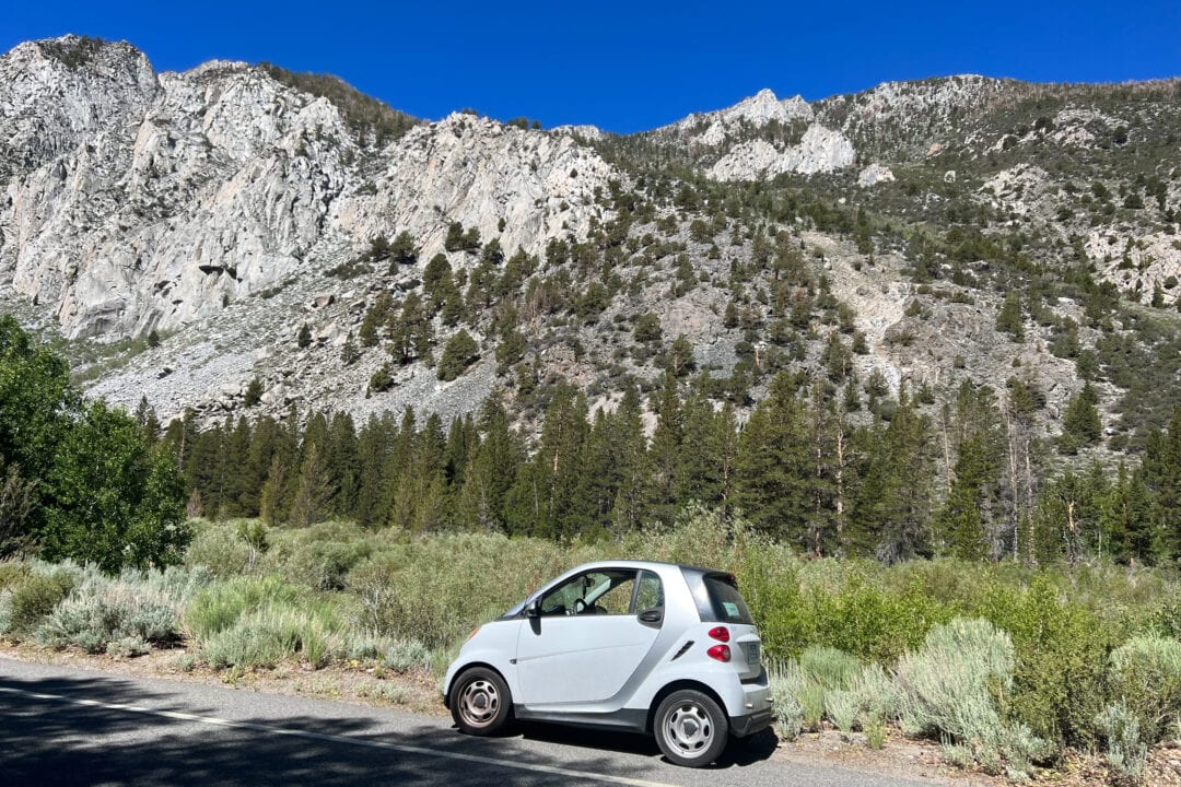 a white smart car parked in front of mountains
