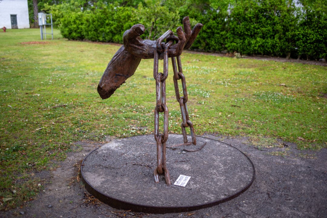 a metal sculpture of a hand tugging at a chain