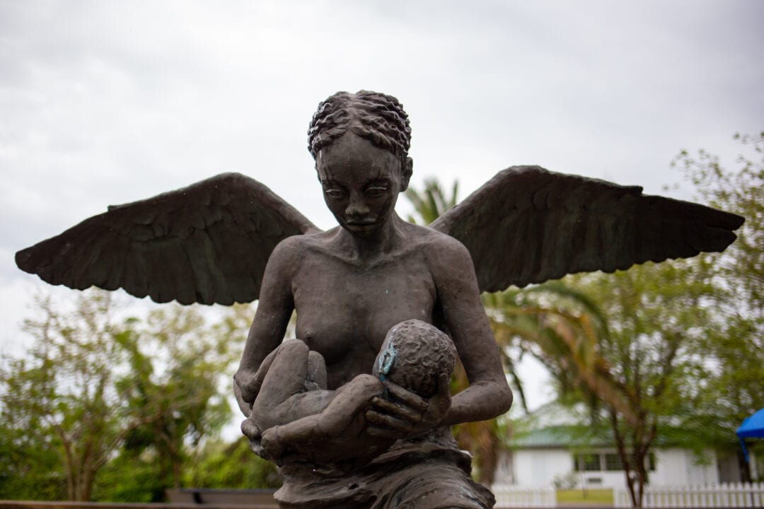 a bronze sculpture of an angel holding a child
