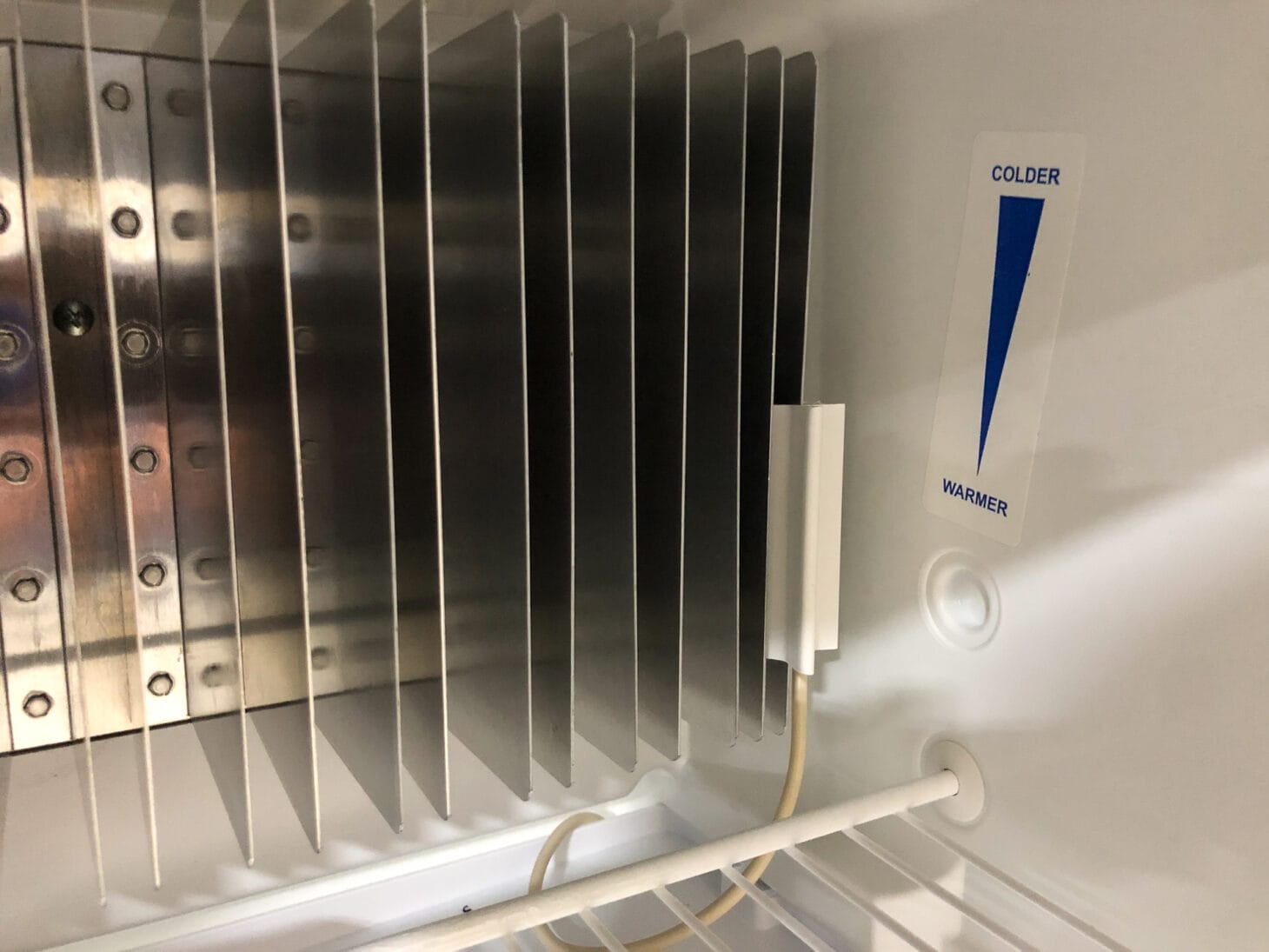Thermistor and evaporator fins with label for "colder" and "warmer" in the back of an RV fridge