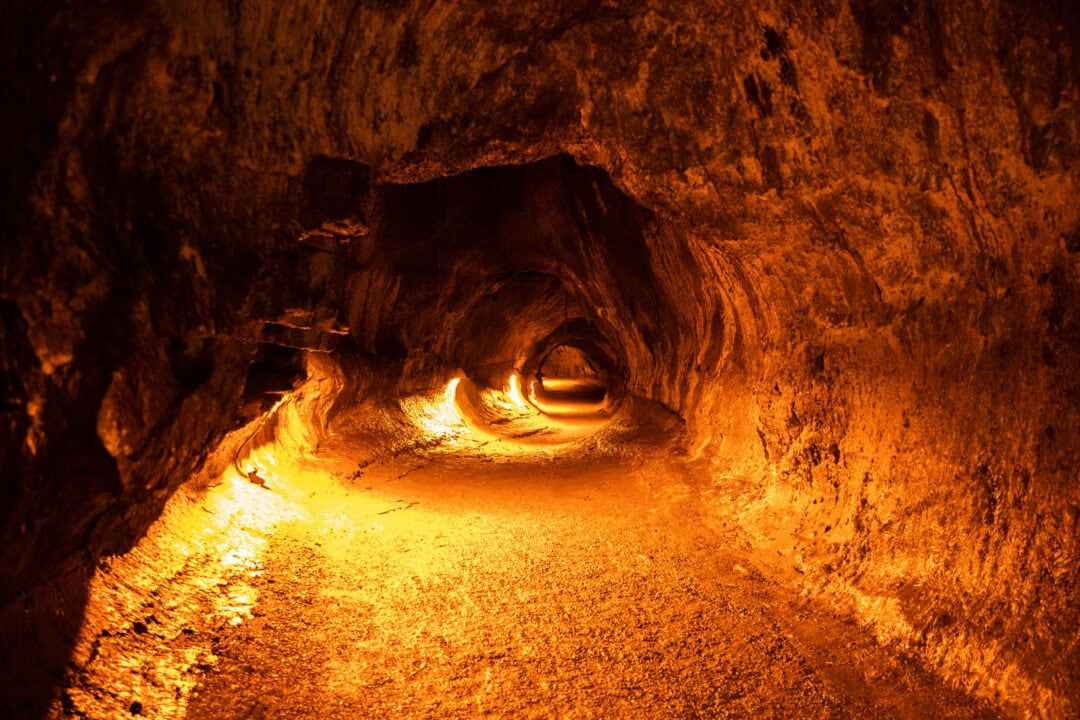 a tunnel carved into rock lit by orange lights