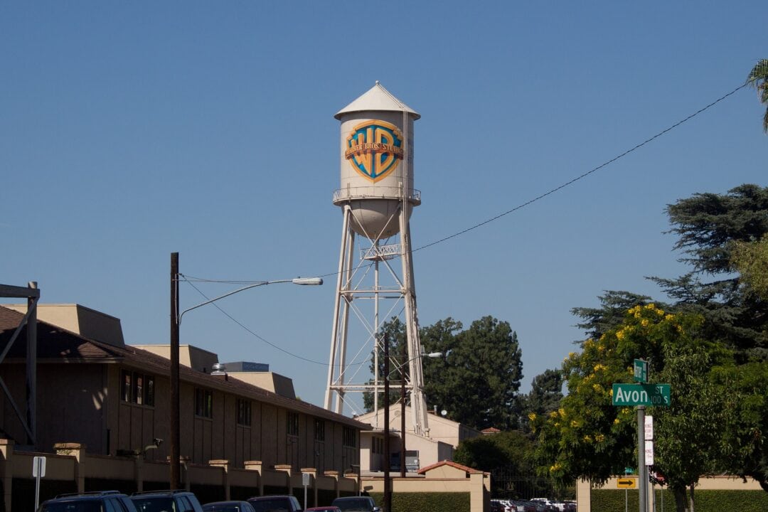 a water tower with the blue and gold warner bros. logo stands above a hollywood studio lot