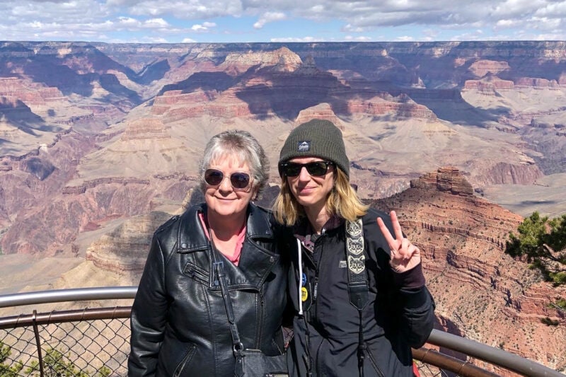 two people in sunglasses pose for a photo in front of the grand canyon