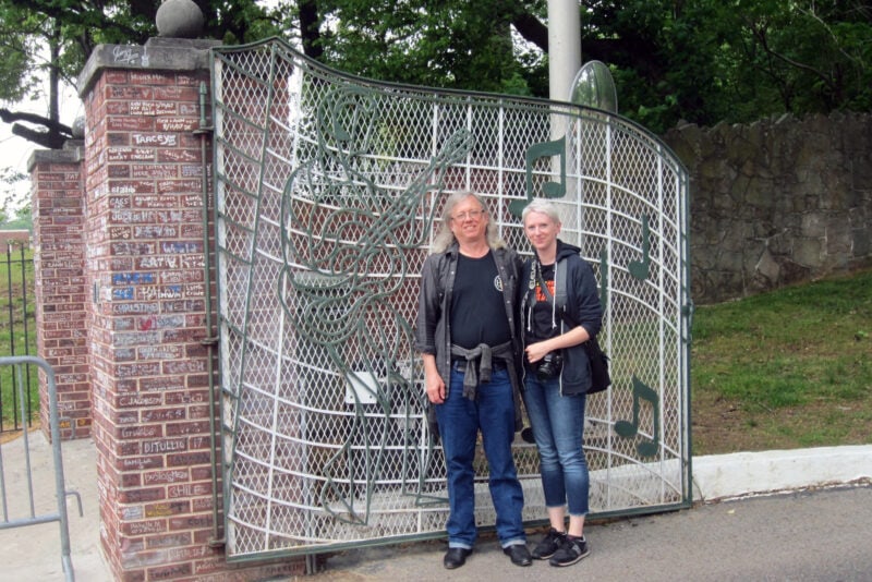 two people stand in front of the gates to graceland, which are decorated with music notes
