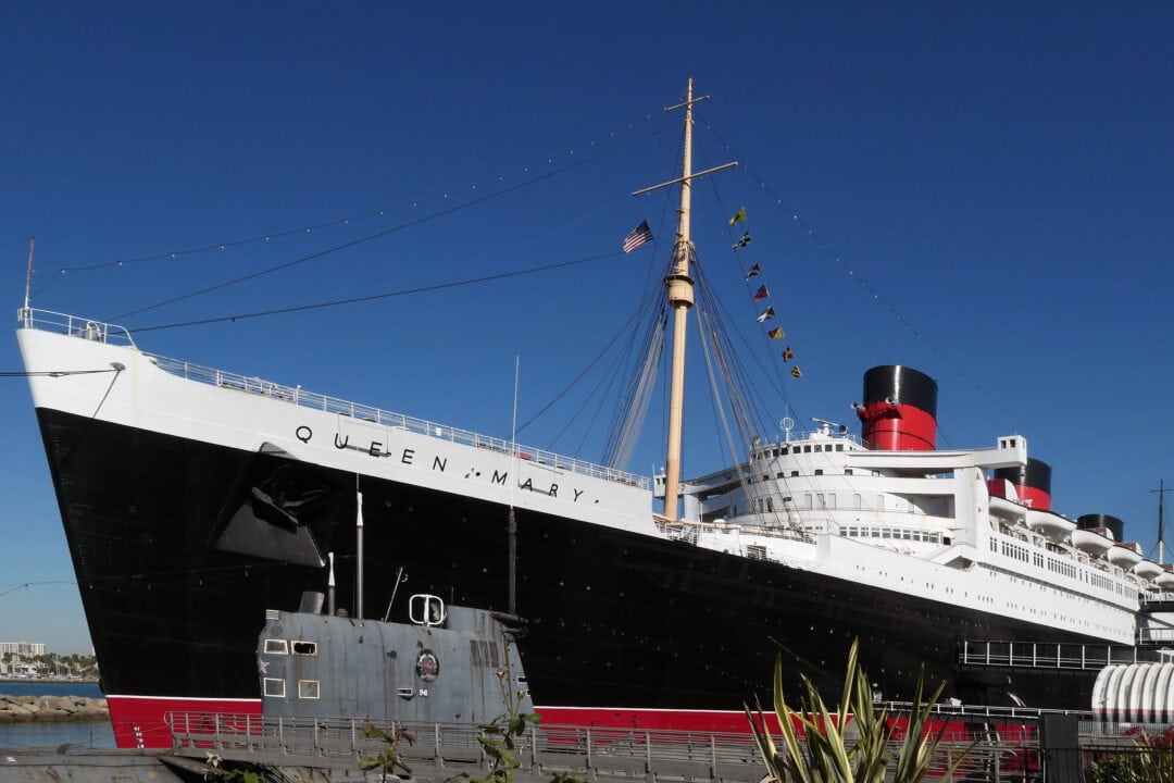 the queen mary, a large black, red and white ocean liner set under a clear blue sky