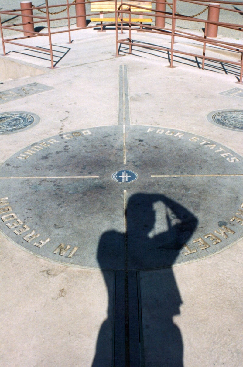 a shadow of a person over the four corners monument marker