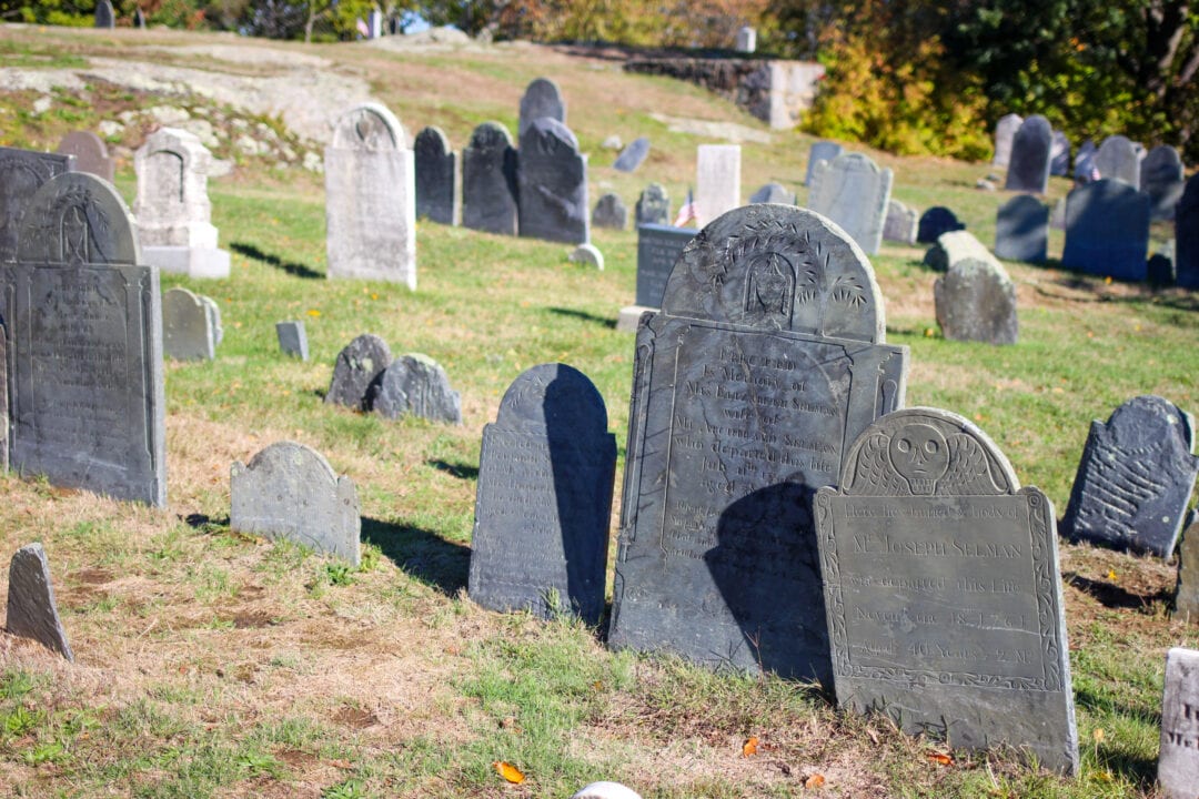 a historic new england cemetery set on a hill with dozens of intricately carved tombstones