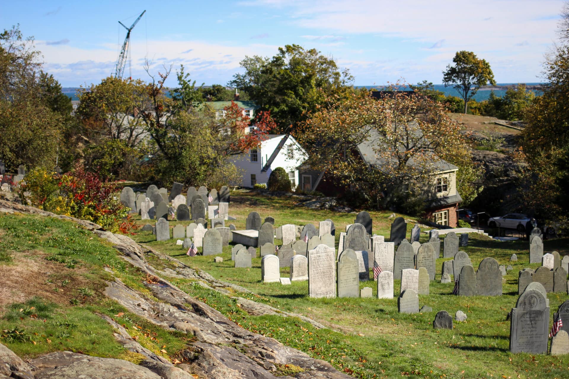 a sloping hillside cemetery with water in the distance
