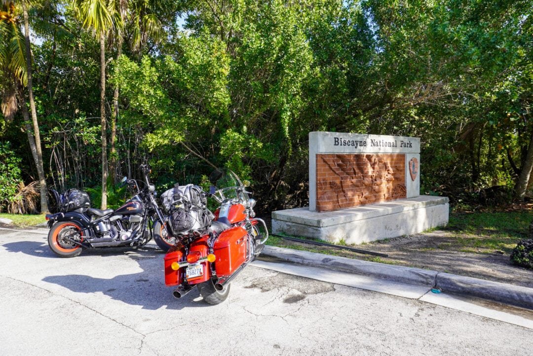 Two motorcycles parked next to a sign that reads "Biscayne National Park"