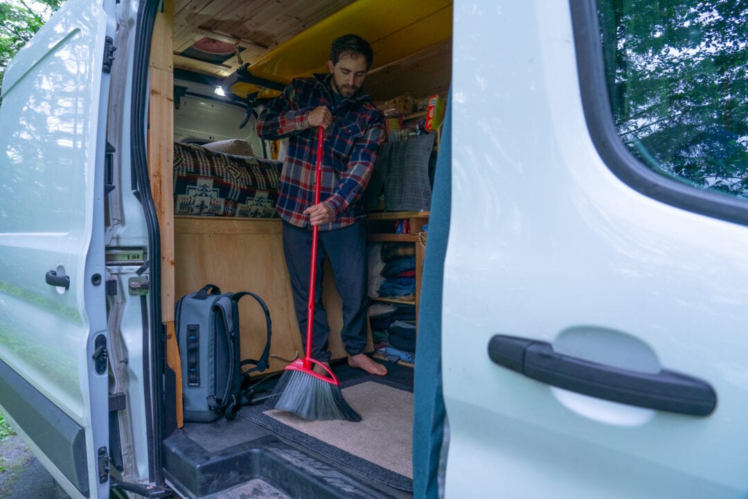 a person sweeps out the back of a converted campervan
