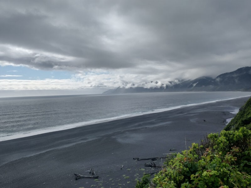 a beach with gray sand under gray clouds