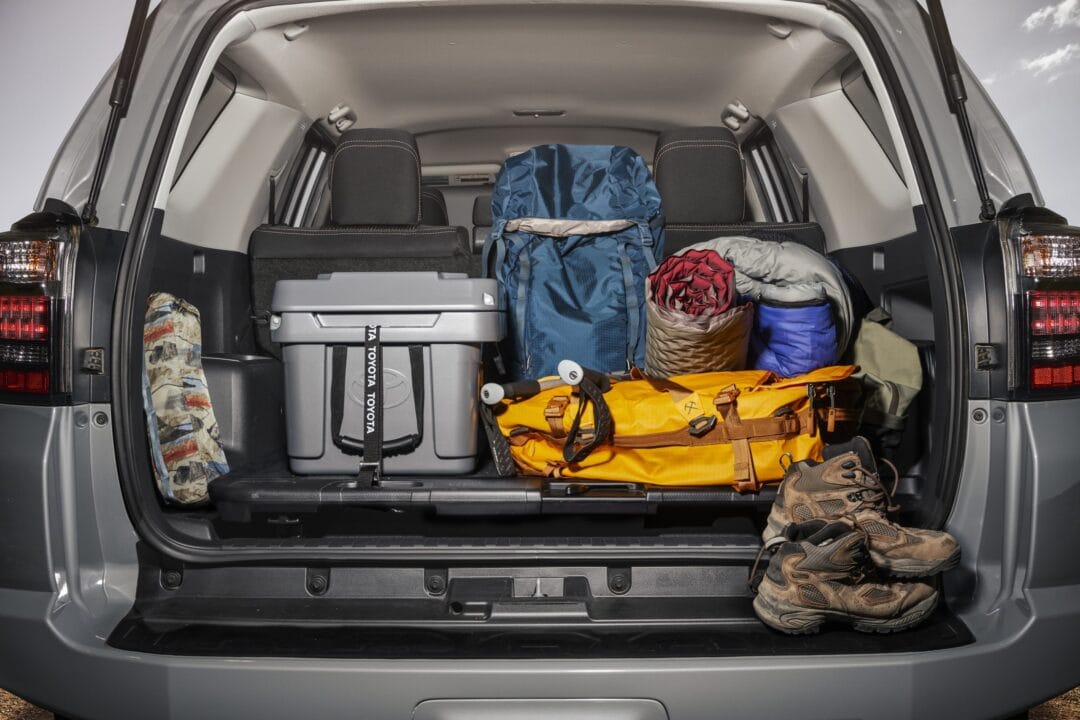an SUV with its trunk open stacked with camping gear