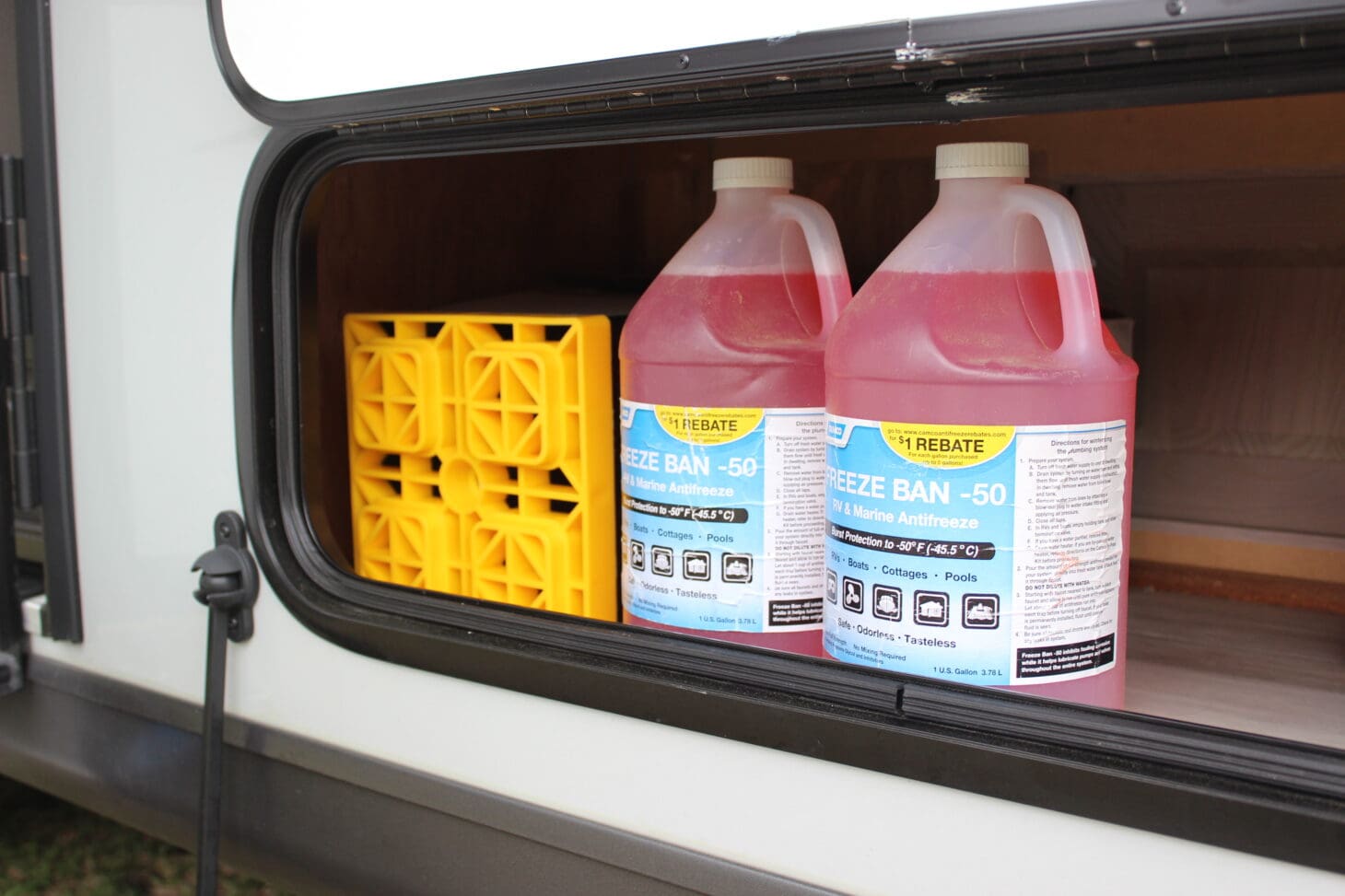 two bottles of pink antifreeze stored in the storage bay of an rv