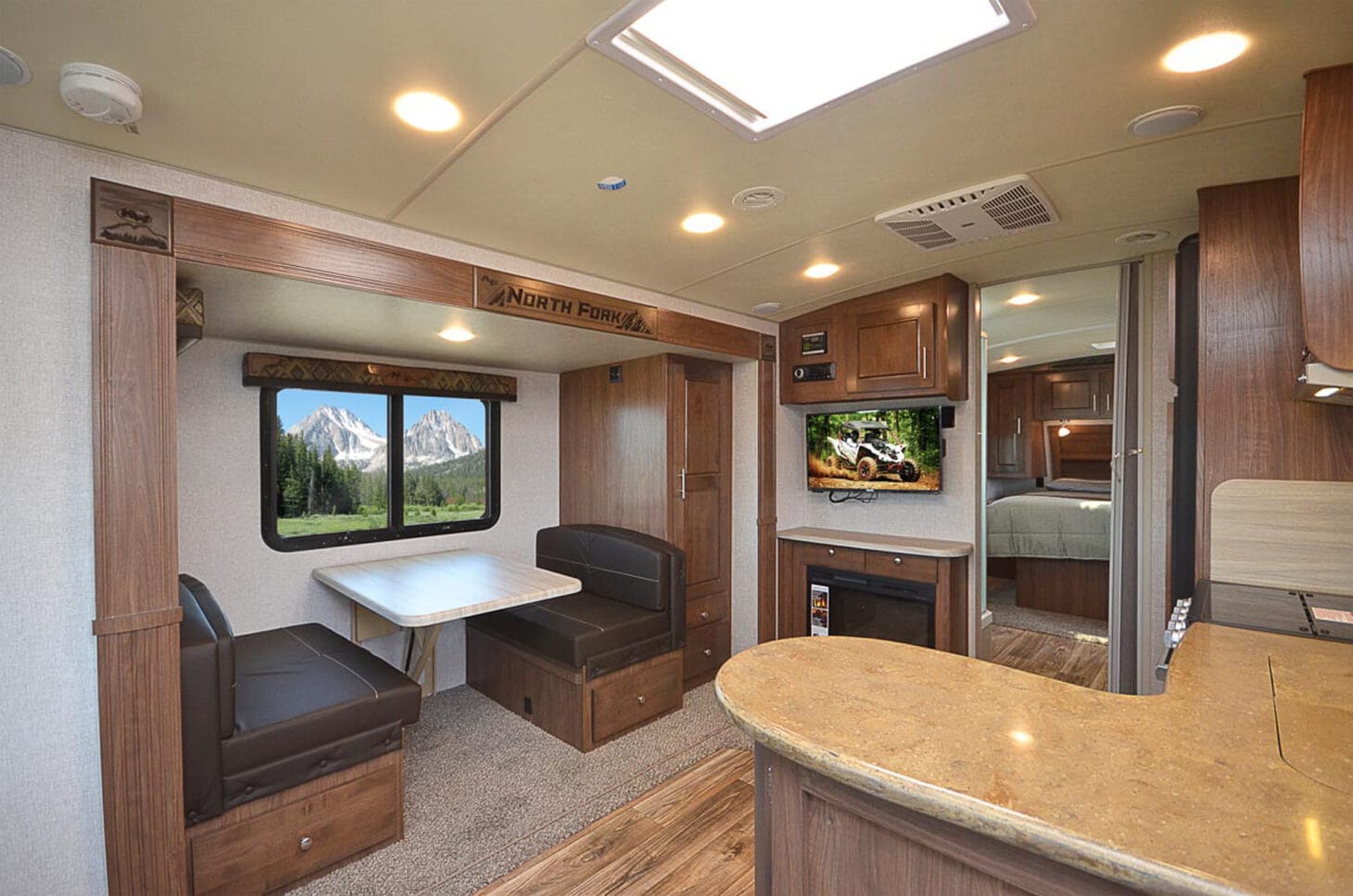Interior of an RV, with a dinette, kitchen, and bedroom in the back