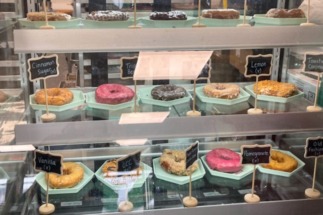 rows of colorful donuts in a bakery case
