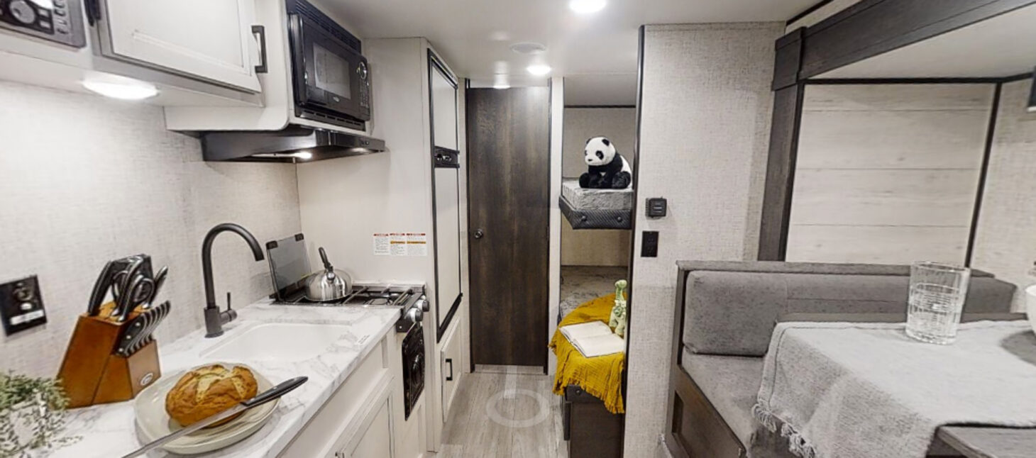 Interior view of small trailer with kitchen, dinette, and bunks
