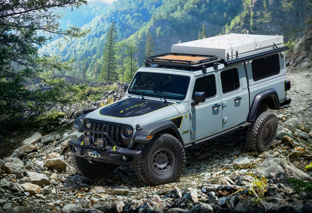 a grey jeep on a rugged rocky mountaintop surrounded by pine trees