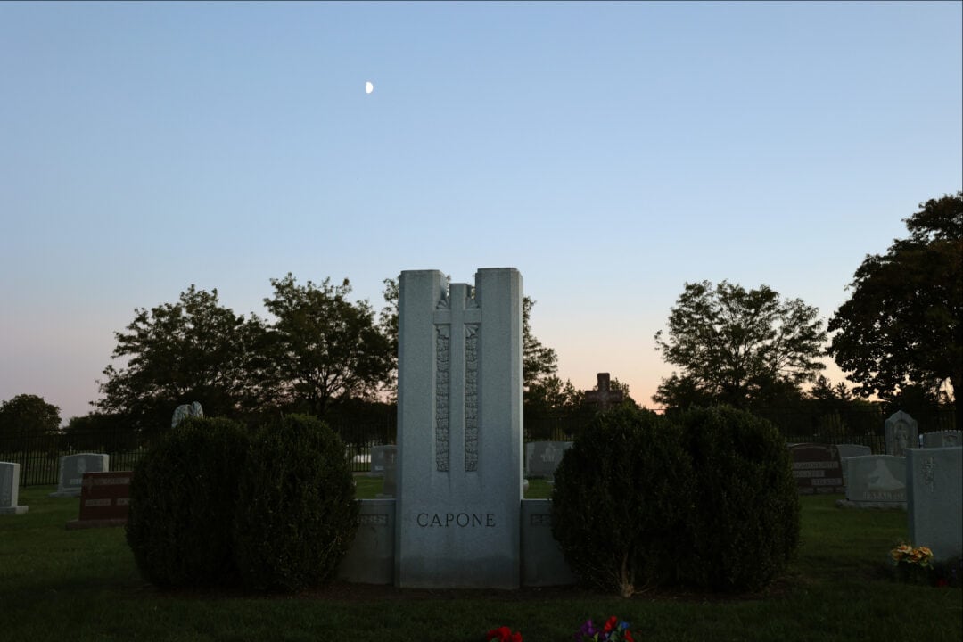 a large marble tombstone for Al Capone at dusk under a half moon