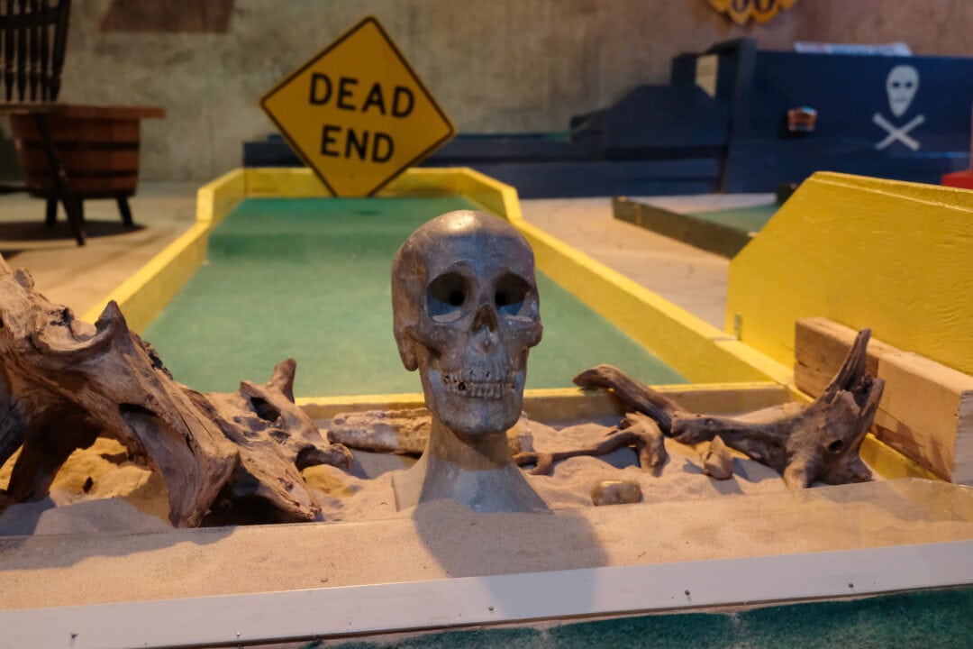 a mini golf course with a dead end sign and a human skull