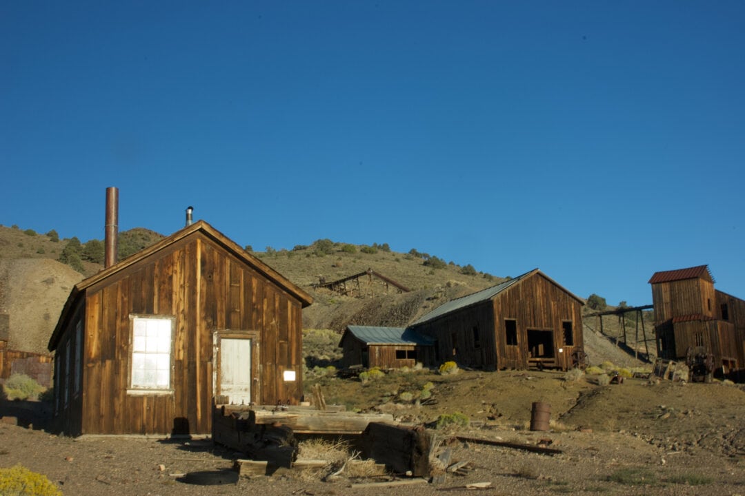 a ghost town with several wooden buildings in the desert set against a clear blue sky