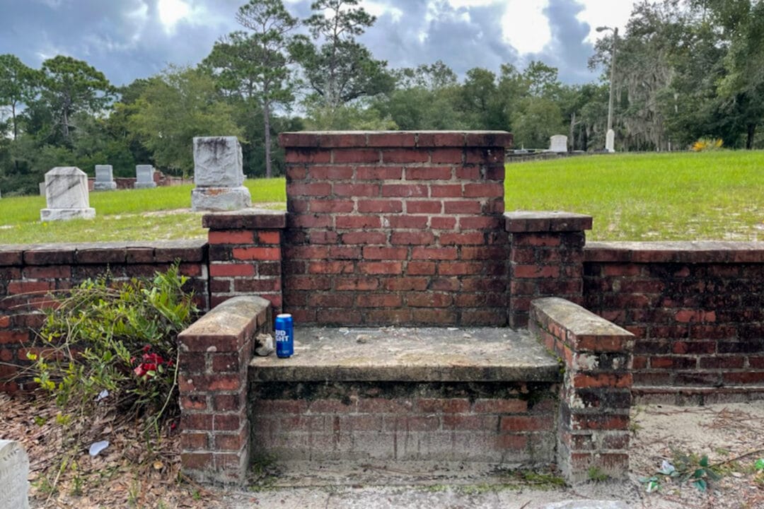 a brick chair in a historic cemetery with a can of bud light sitting on the seat