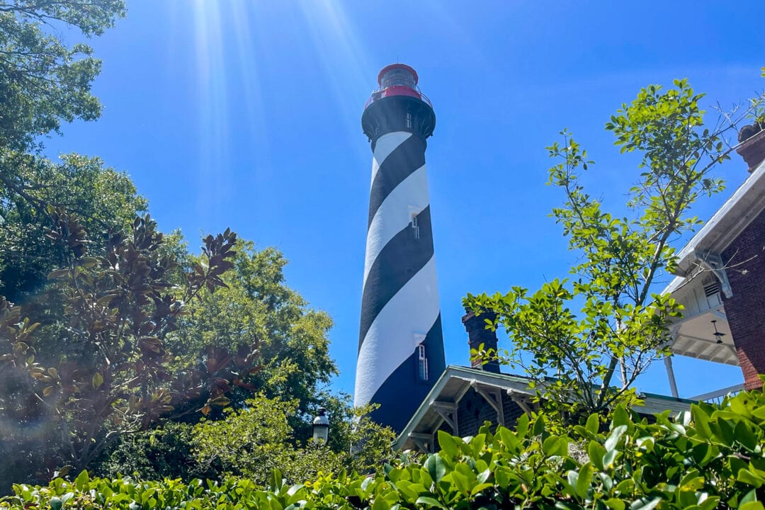 a black and white striped lighthouse against a clear blue sky