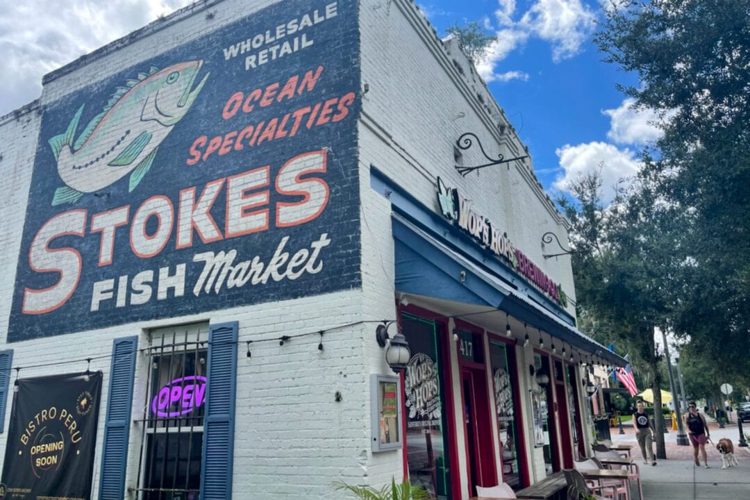 a small brick brewery with a sign painted on the side that says "wholesale retail ocean specialties stokes fish market" with a painting of a fish