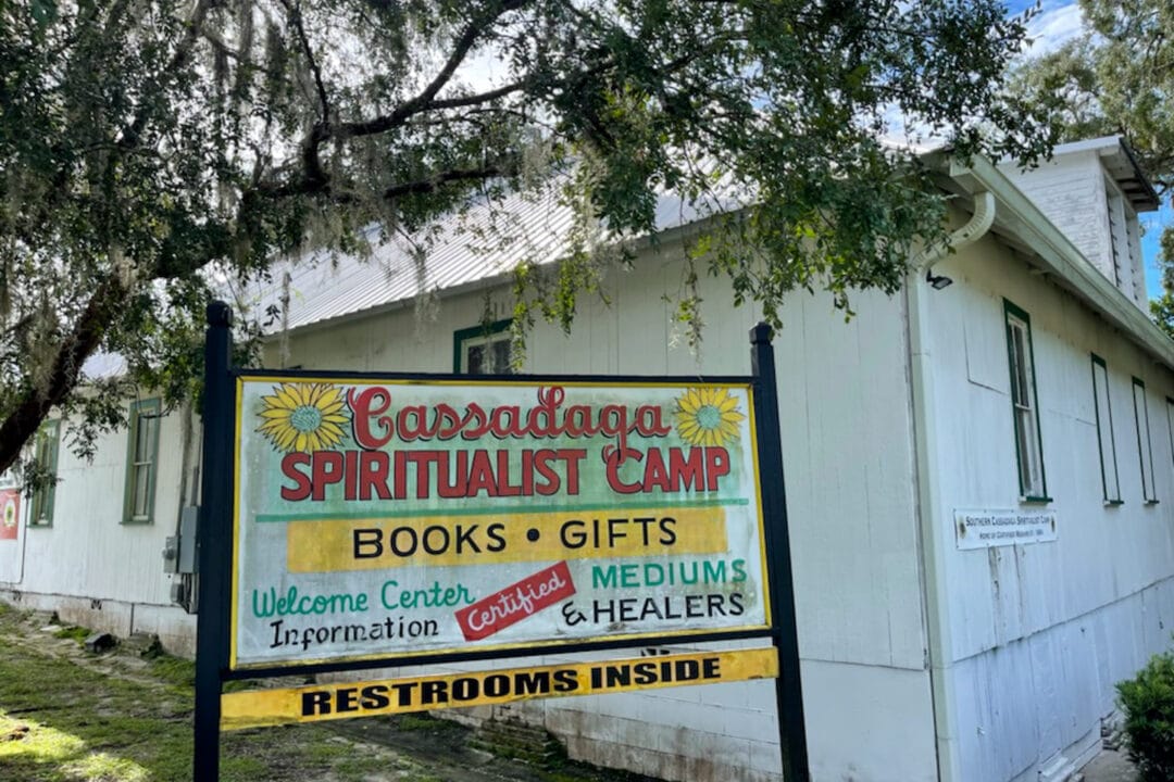 A sign for the cassadaga spiritualist camp next to a small white building