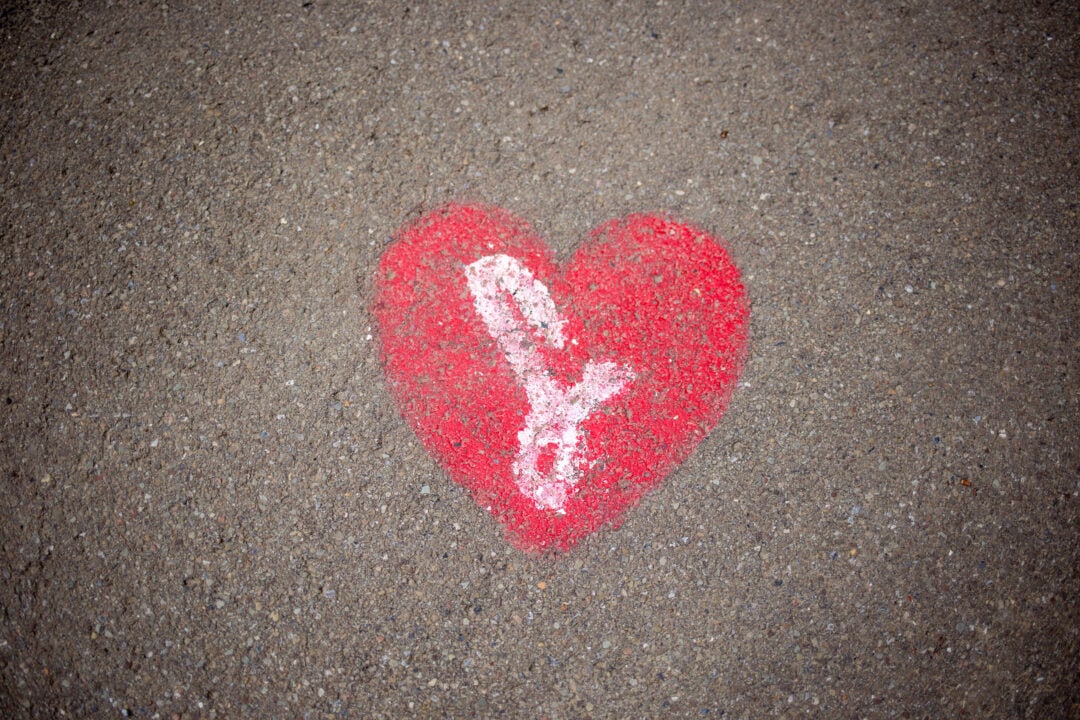 a red heart with a script L painted on asphalt