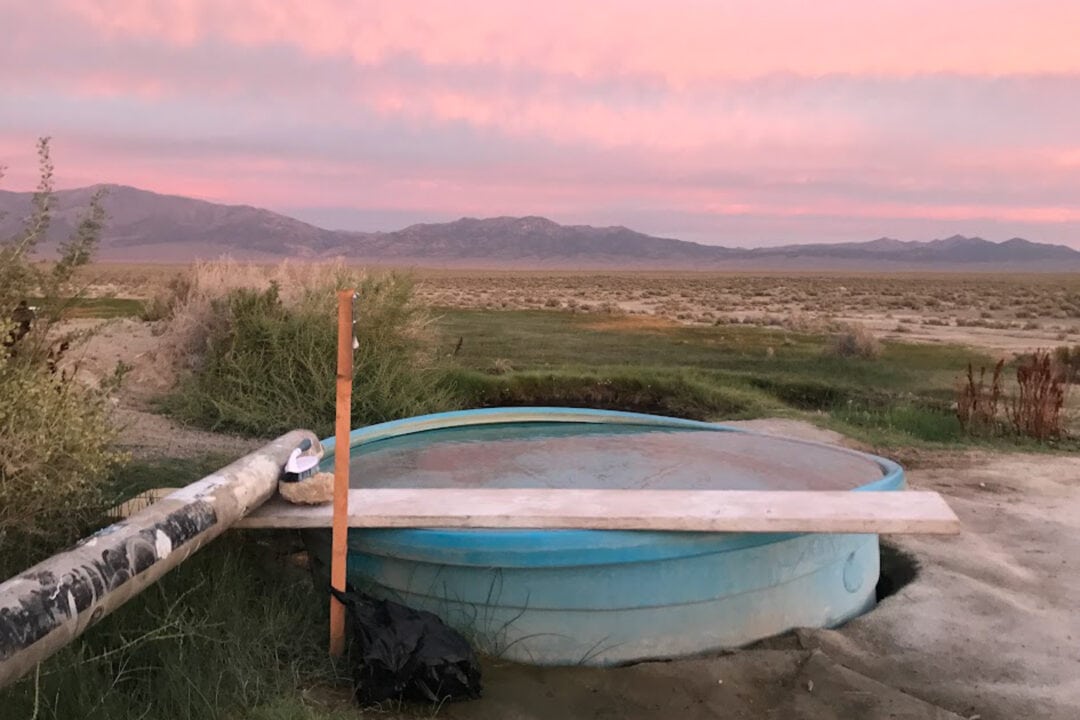 a pool with hot springs in the desert at sunset