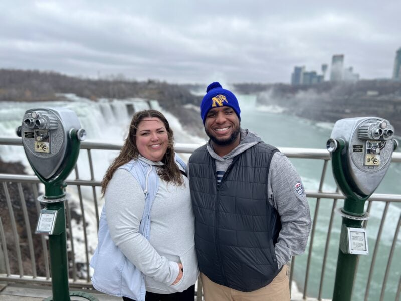 two people pose for a photo in front of an overlook at niagara falls