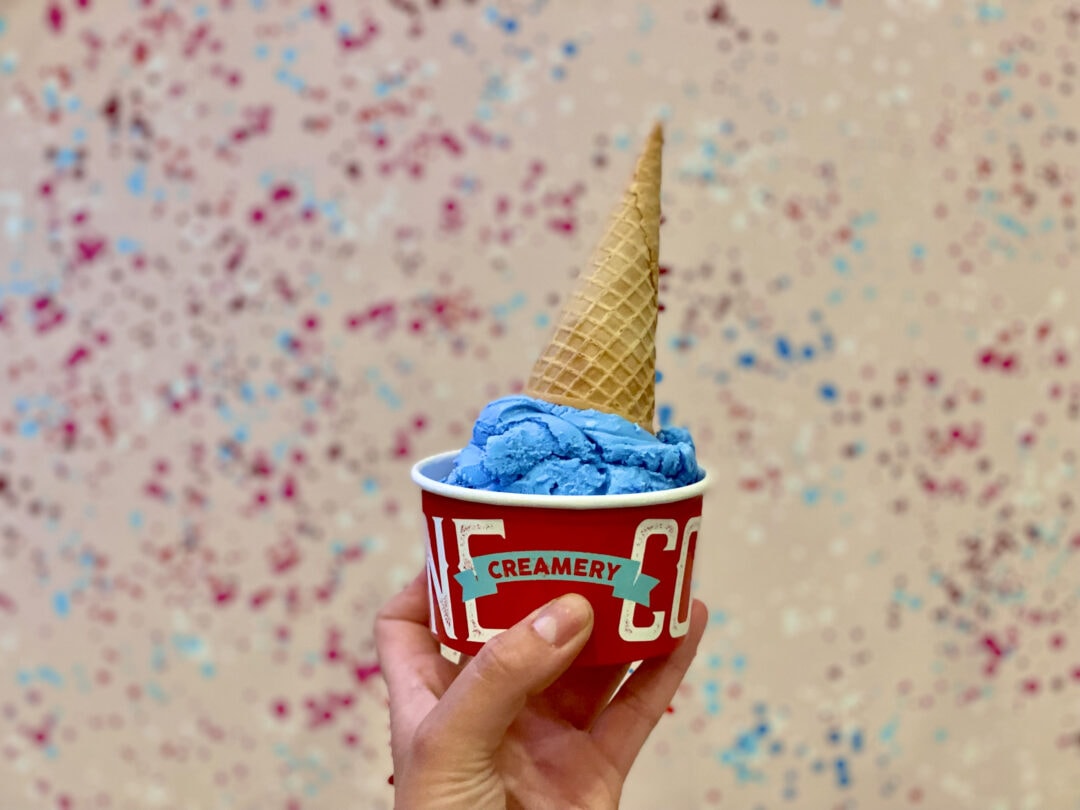 Bright blue ice creak in a sugar cone stands out against a bespeckled backdrop.
