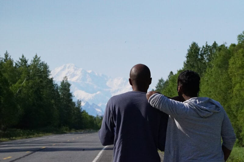 A couple looks onwards at a snowy mountain peak in the distance.