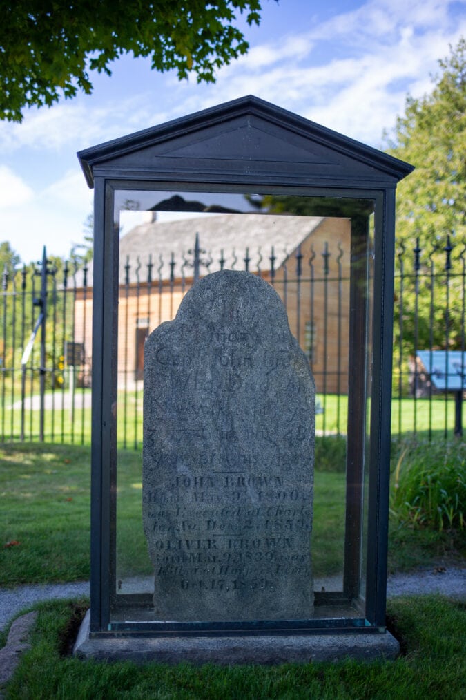 a tombstone in a graveyard enclosed in a glass box