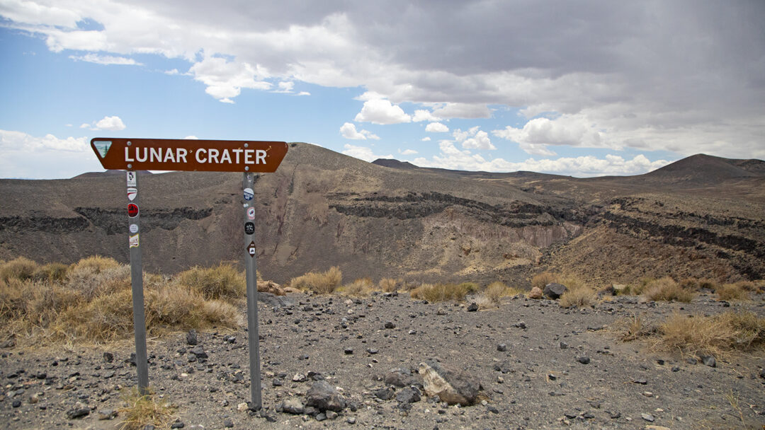 A sign reads 'Lunar Crater' in front of a desert crater landscape