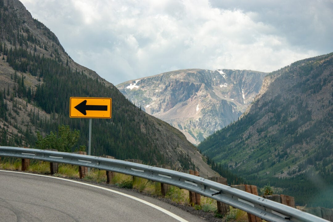 A sharp turn in a mountain road is indicated with an arrow sign.
