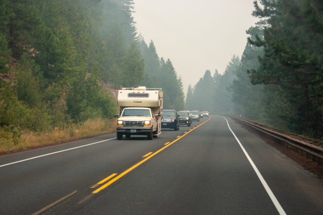A driver with an RV blocks a long row of traffic as cars cannot pass on a narrow mountain road.