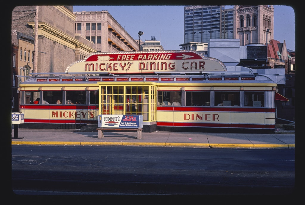 a railroad-style dining car with red and white trim and a large sign that says "mickey's dining car"