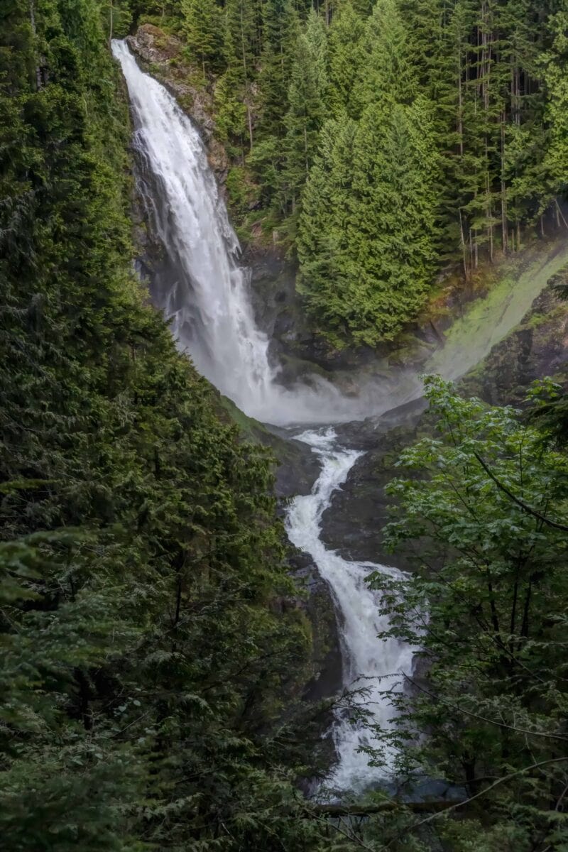A steep waterfall cascades down a lush mountainside.