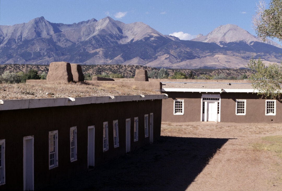 A single-story building lined with windows and doors stands amongst a mountainous backdrop.