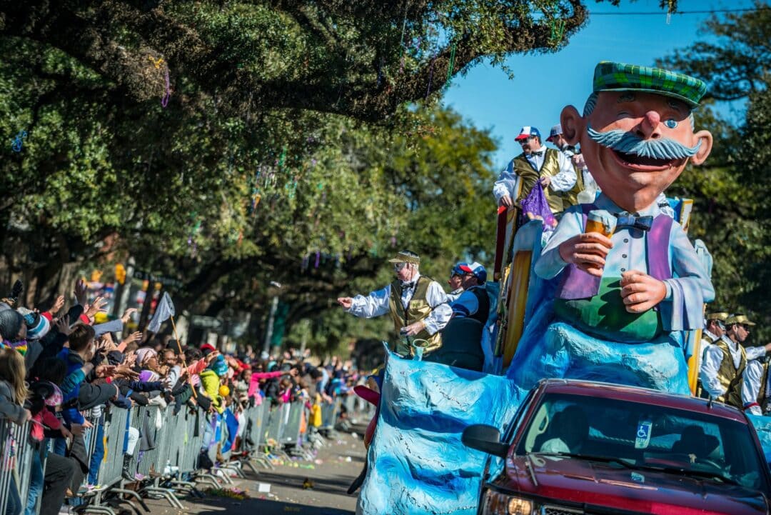 People toss beads from wacky, colorful parade floats while driving down a street in Mobile, Alabama.