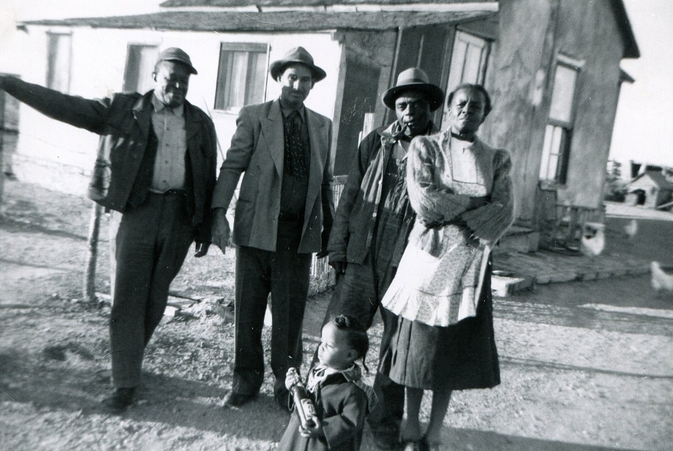 A black and white photo showcases four adults and one child dressed in old-fashioned attire.