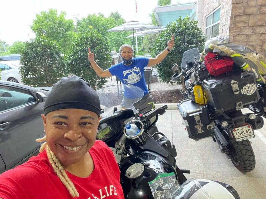 Two women smiling next to their fully packed motorcycles
