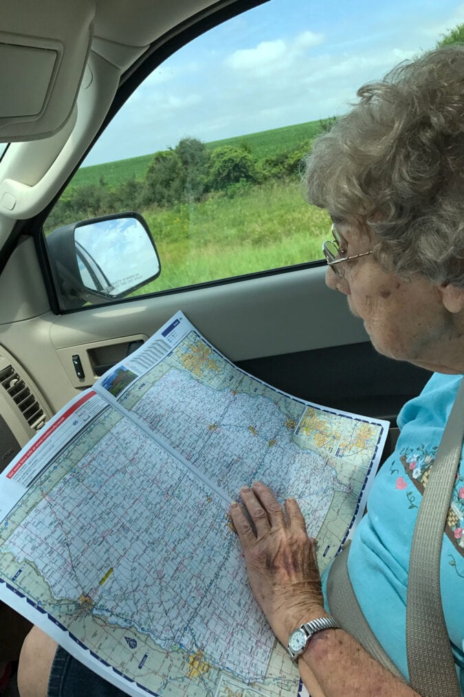 A woman reads a map from the passenger side of a car.