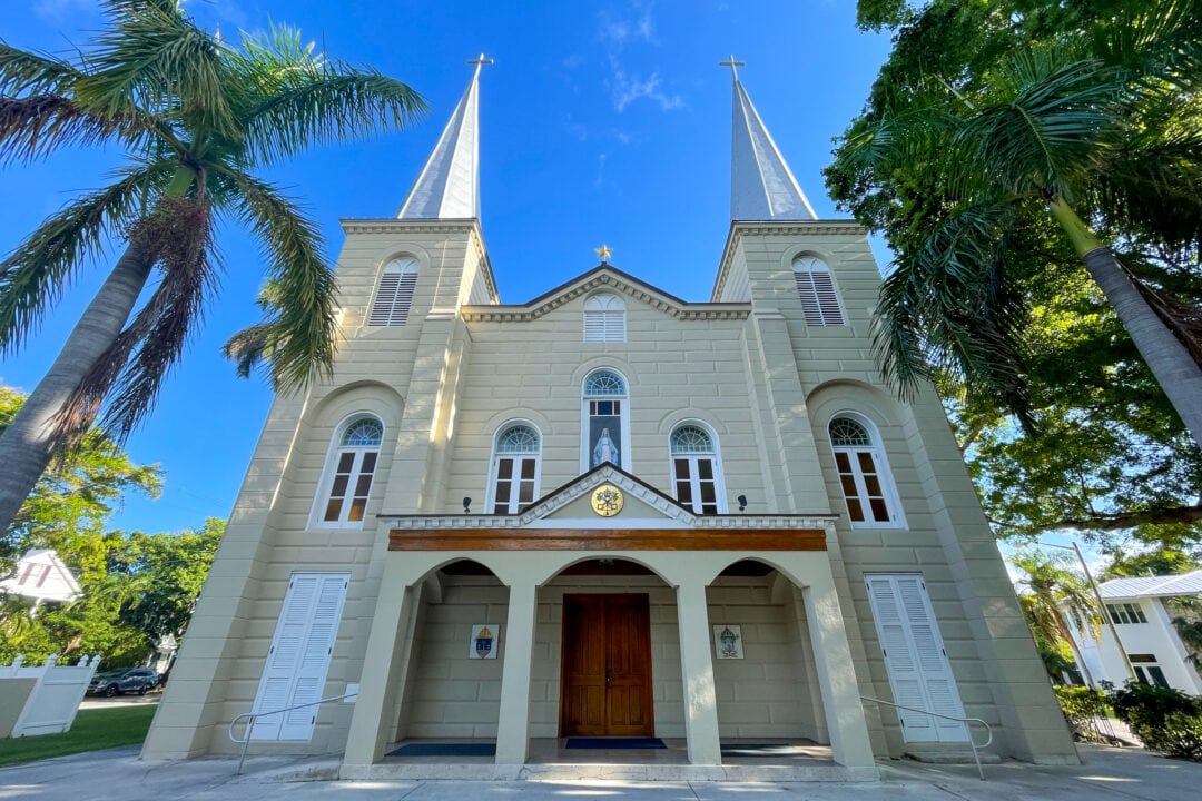 A small church is surrounded by palm trees.