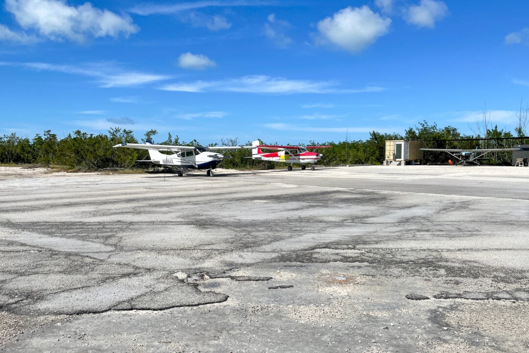 Several small engine planes sit on a rugged tarmac.